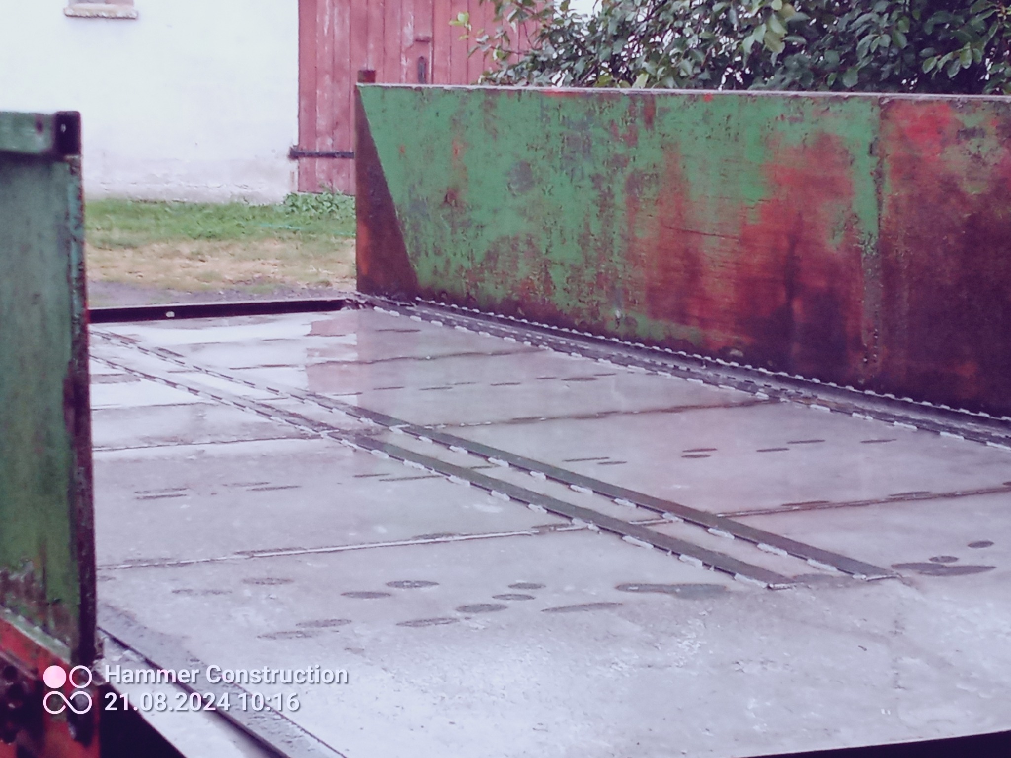 Wnętrze przyczepy rolniczej z blachy stalowej, widoczne spawy i ślady korozji na zielonej burcie.