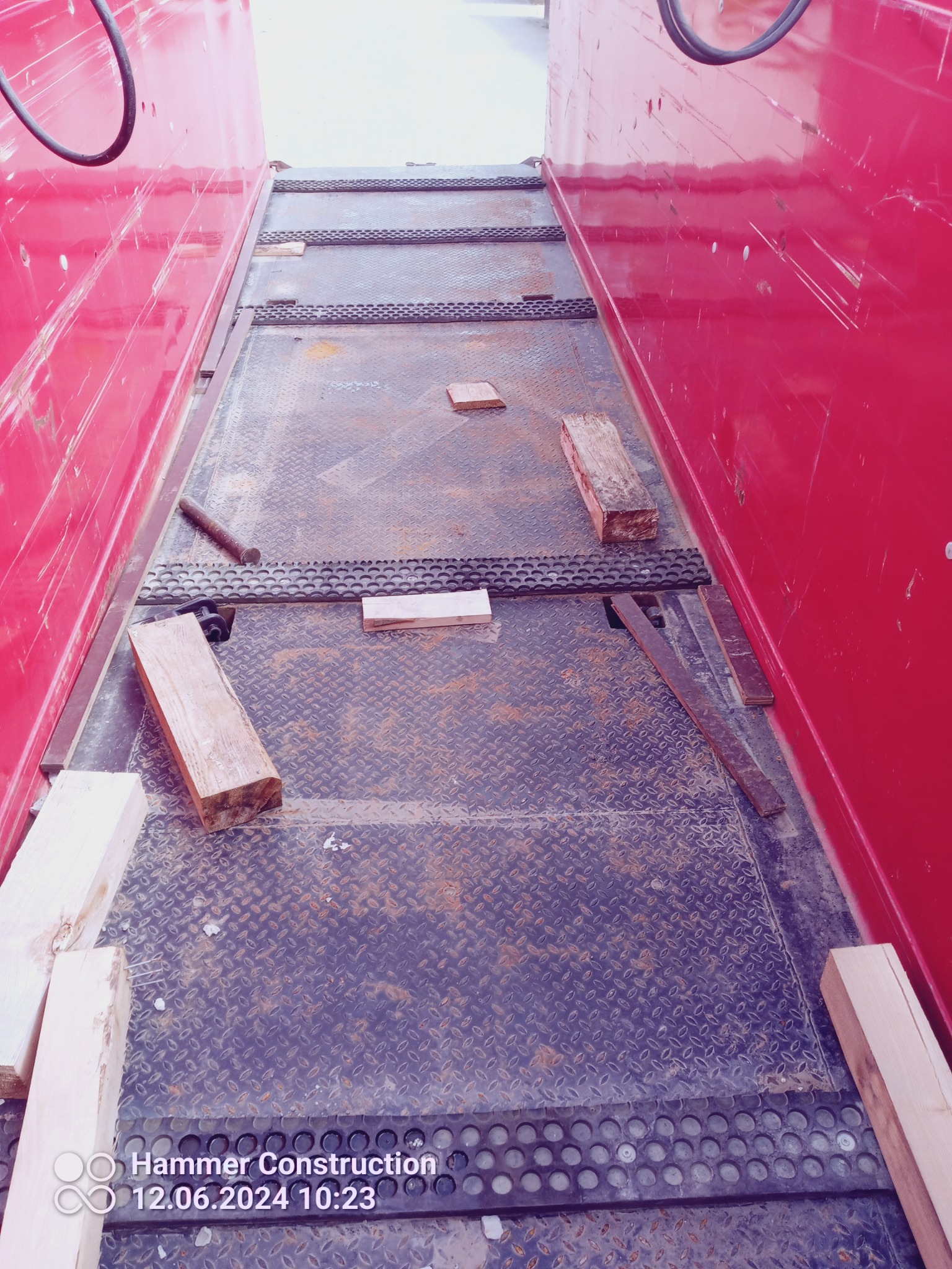 Wnętrze przestrzeni roboczej z blachą ryflowaną, drewnianymi klockami i metalowymi elementami, prawdopodobnie w trakcie budowy lub remontu.