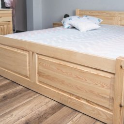 LUK-MEB Meble na wymiar - Drewniane łóżko z sosnowymi szafkami nocnymi i komodą w jasnym pokoju z panelami podłogowymi.