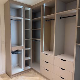 LUK-MEB Meble na wymiar - Jasna, narożna szafa wnękowa z szufladami i oświetleniem LED, widok z perspektywy wnętrza pomieszczenia, parkiet w jodełkę na podłodze.