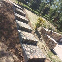 GIB-STONE MATEUSZ GIBEK - Kamienne schody ogrodowe z betonowymi obrzeżami w trakcie budowy, widoczne narzędzia i świeżo przekopana ziemia.