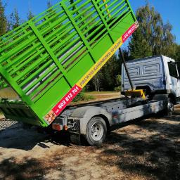 Ciężarówka z zieloną skrzynią załadowczą, na której widnieje żółty baner reklamowy z numerem telefonu i napisem 'Drewno Kominkowe Opałowe'.