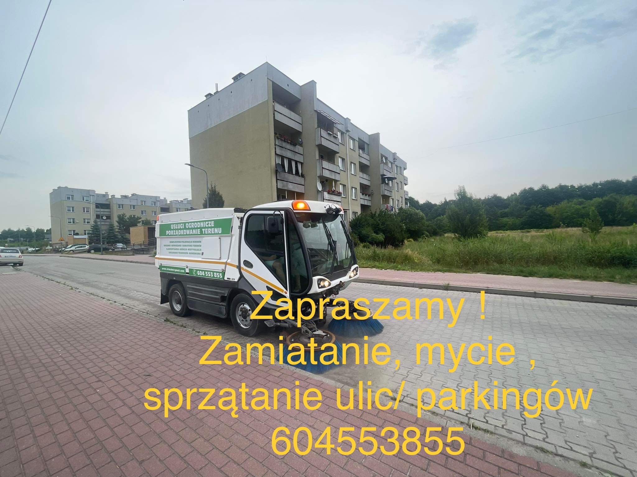 Pojazd do zamiatania ulic z napisem 'Usługi ogrodnicze, porządkowanie terenu' na tle bloku mieszkalnego i zieleni.