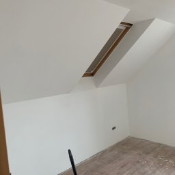 MJ GARDEN Marian Jarek - Poddasze po malowaniu na biało, widoczne okno dachowe, ślady farby na panelach podłogowych i wystające gniazdko elektryczne.