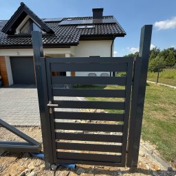 FOXsteel - Nowoczesna, pozioma brama wjazdowa w kolorze antracytu w Zagórzanach. Widoczny dom z panelami słonecznymi i podjazd z kostki brukowej. Minimalistyczny design.