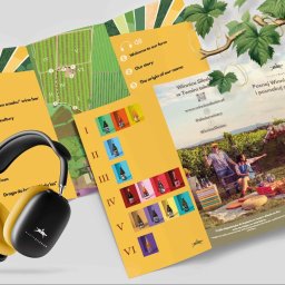 IYO CREATIVE SPÓŁKA Z OGRANICZONĄ ODPOWIEDZIALNOŚCIĄ - Kreatywna kompozycja materiałów reklamowych Winnicy Silesian: mapa winnicy z zaznaczonymi punktami, katalog win z kolorowymi etykietami, zdjęcie degustacji w winnicy oraz słuchawki z logo firmy...