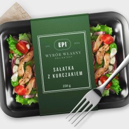 IYO CREATIVE SPÓŁKA Z OGRANICZONĄ ODPOWIEDZIALNOŚCIĄ - Zdjęcie opakowania sałatki z kurczakiem marki EPI, na czarnej tacce, z widelcem obok, na jasnym tle.