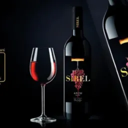 Etykieta nominowanego armeńskiego wina Sirel z motywem winogron i korkociągu, prezentowana obok kieliszka czerwonego wina i logo konkursu ART OF PACKAGING na ciemnym tle.