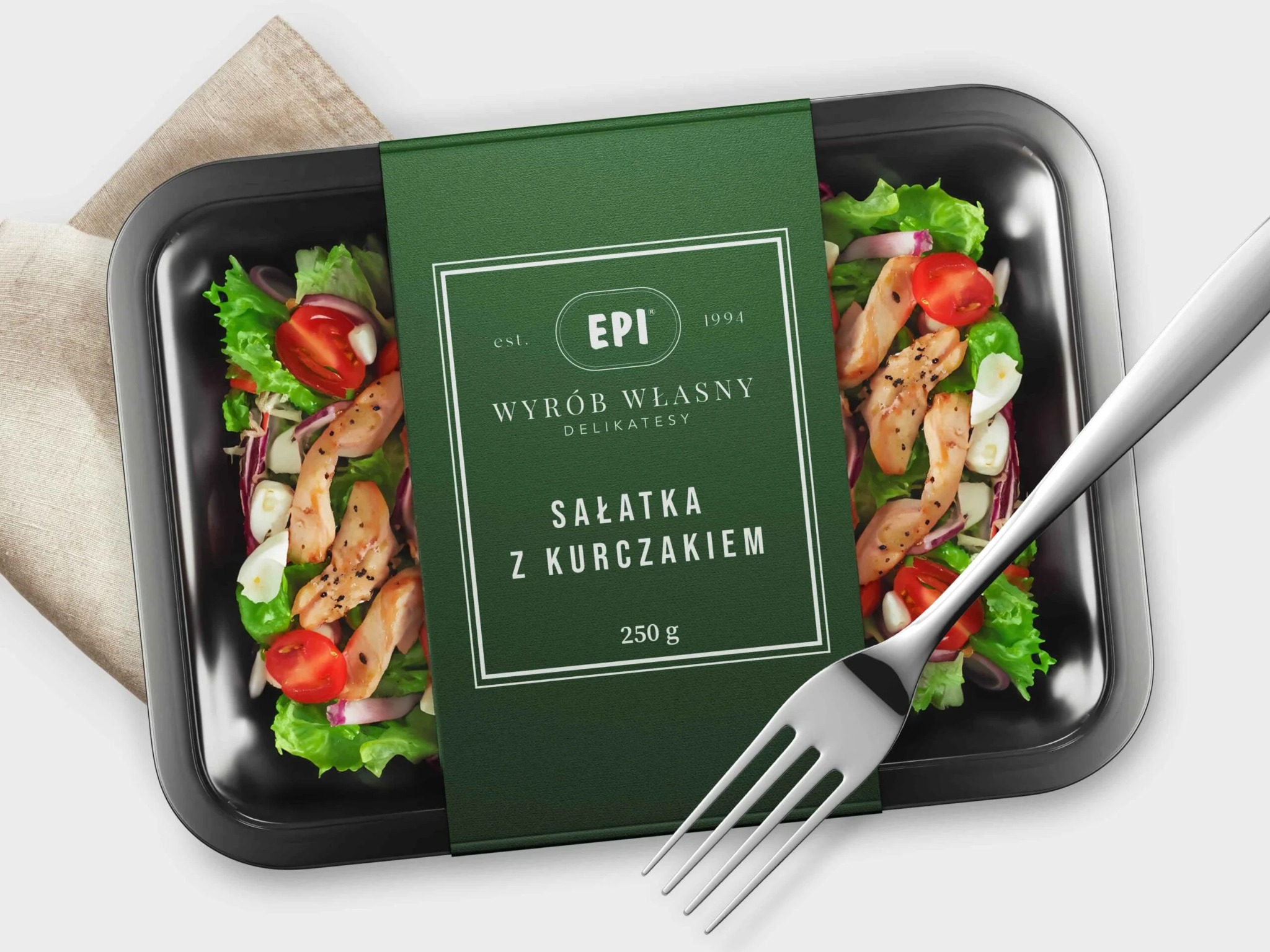 Zdjęcie opakowania sałatki z kurczakiem marki EPI, na czarnej tacce, z widelcem obok, na jasnym tle.