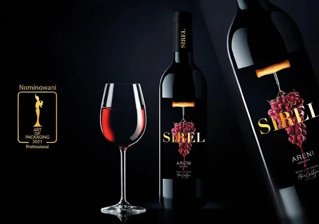 Etykieta nominowanego armeńskiego wina Sirel z motywem winogron i korkociągu, prezentowana obok kieliszka czerwonego wina i logo konkursu ART OF PACKAGING na ciemnym tle.