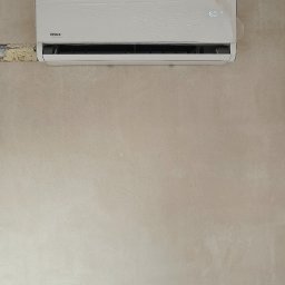 Piotr Groński AIRCOOL TECH - Biała klimatyzacja VIVAX zamontowana na surowej ścianie. Urządzenie jest jeszcze w folii ochronnej, wyświetlacz pokazuje temperaturę 16 stopni Celsjusza.