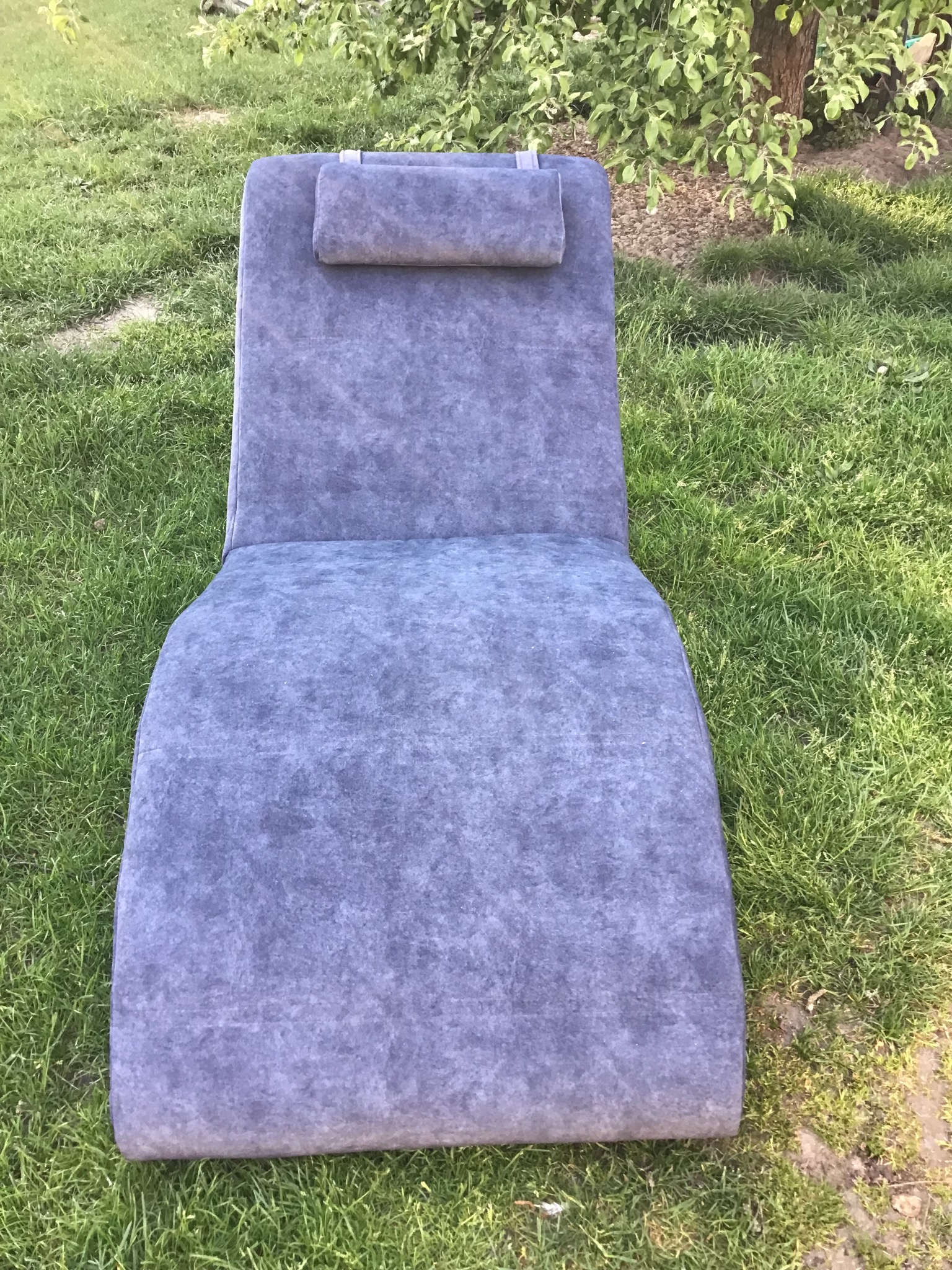 Tapicerowany leżak ogrodowy z zagłówkiem, ustawiony na trawie w słoneczny dzień.