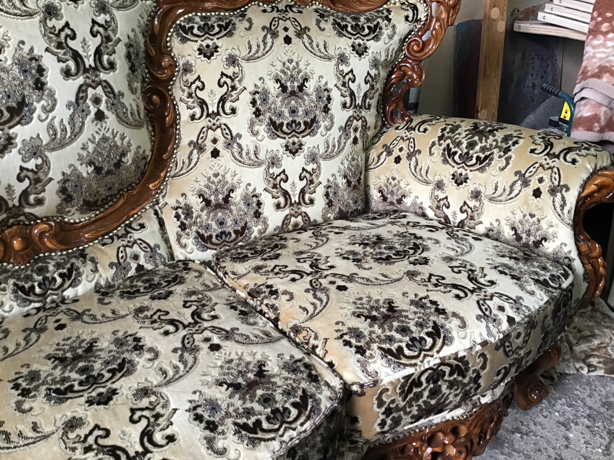 Odrestaurowany fotel z ozdobną, wzorzystą tapicerką w odcieniach beżu i brązu, drewniane rzeźbione elementy ramy z widocznymi detalami.