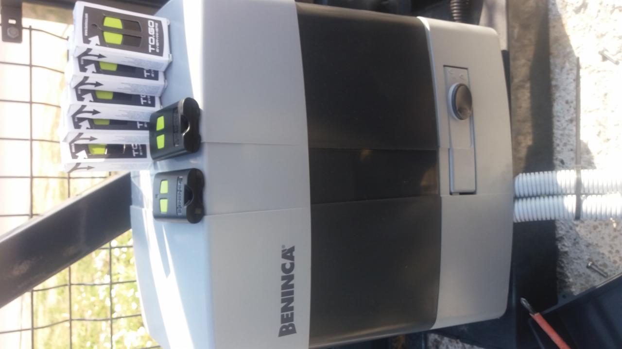 Siłownik bramy Beninca z pilotami TO.GO i przewodami w peszlu, widoczne logo producenta.