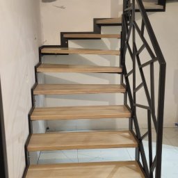 Geso Steel - Schody metalowe z drewnianymi stopniami i designerską balustradą z czarnego metalu, widok z dołu, w tle okno i fragment ściany.