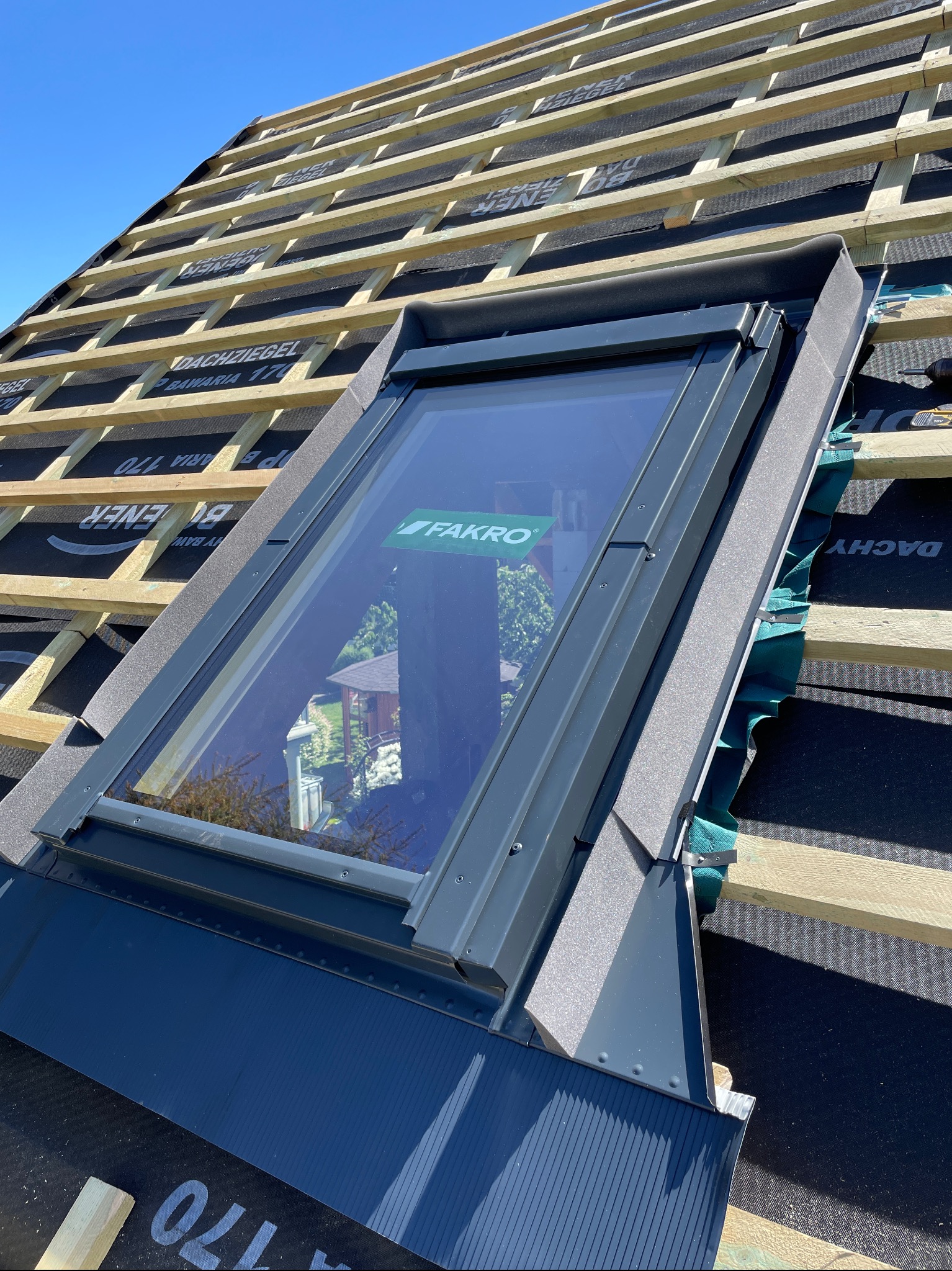 Montaż okna dachowego Fakro na membranie dachowej z łatami, widoczne obróbki blacharskie i uszczelnienia