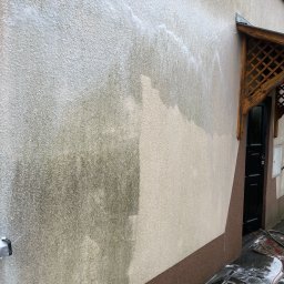 Jarosław Łukasiewicz - Fragment elewacji budynku w trakcie czyszczenia pod ciśnieniem. Widoczna różnica między umytą a zabrudzoną powierzchnią, piana na kostce brukowej.