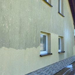 Jarosław Łukasiewicz - Fragment elewacji domu z widoczną różnicą po czyszczeniu, od dołu do połowy ściany. Widoczne okna i kamienna podmurówka. Ślady wody na kostce brukowej.