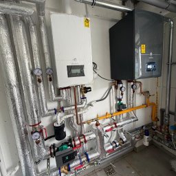 SANTERM - Profesjonalnie wykonana instalacja centralnego ogrzewania z dwoma kotłami De Dietrich (białym i ciemnym), rurami w srebrnej izolacji, miedzianymi i gazowymi, z widocznymi zaworami i pompami...