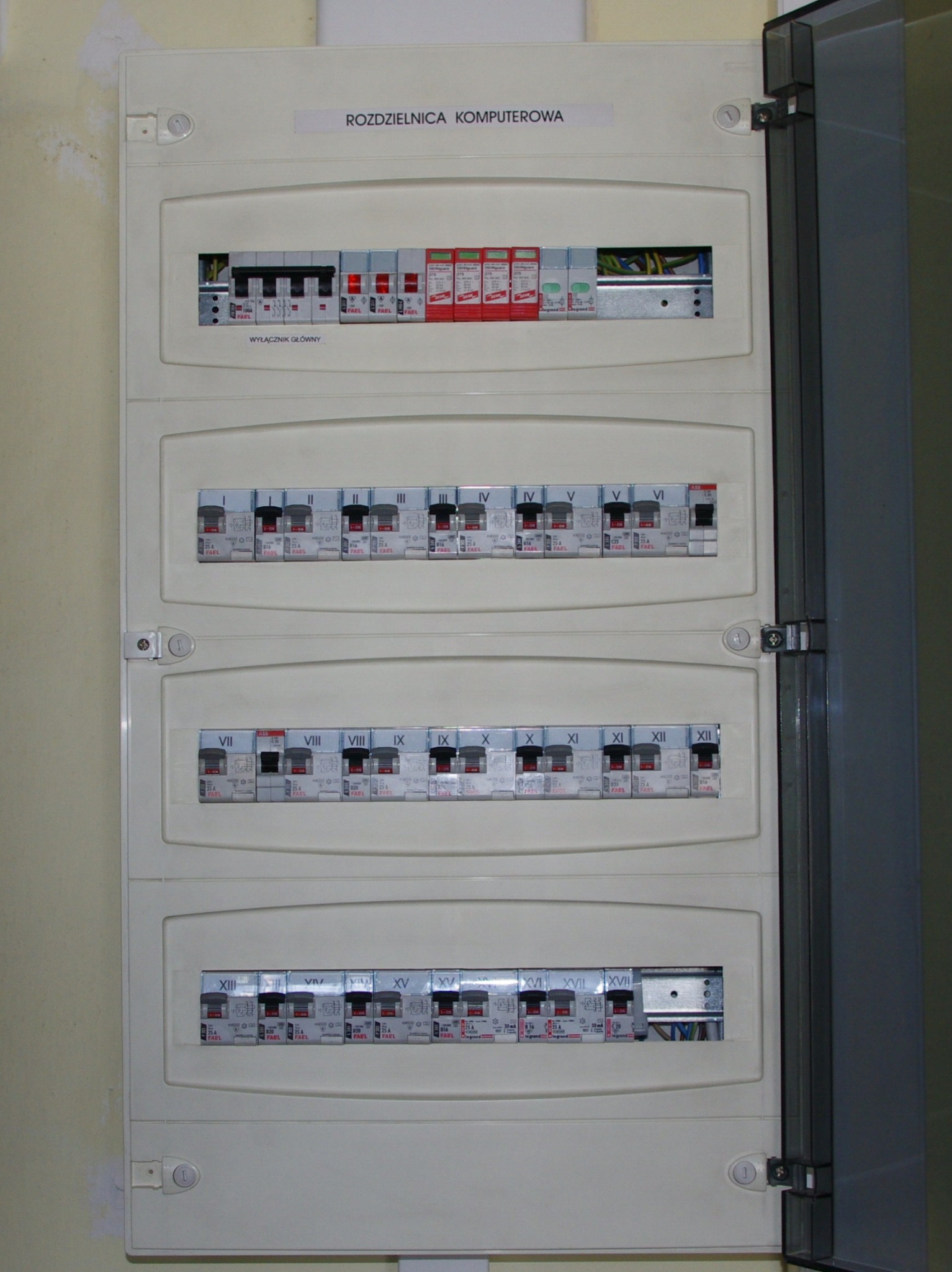 Rozdzielnica komputerowa z widocznymi bezpiecznikami i wyłącznikiem głównym, z otwartymi drzwiczkami po prawej stronie.