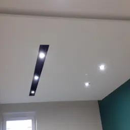 Podwieszany sufit z oświetleniem LED w nowocześnie wykończonym wnętrzu. Widoczny fragment ściany pomalowanej na zielono.