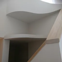 Nietypowa, falista zabudowa z płyt karton-gips w jasnym wnętrzu, z widoczną drewnianą listwą i kwiatami w tle.