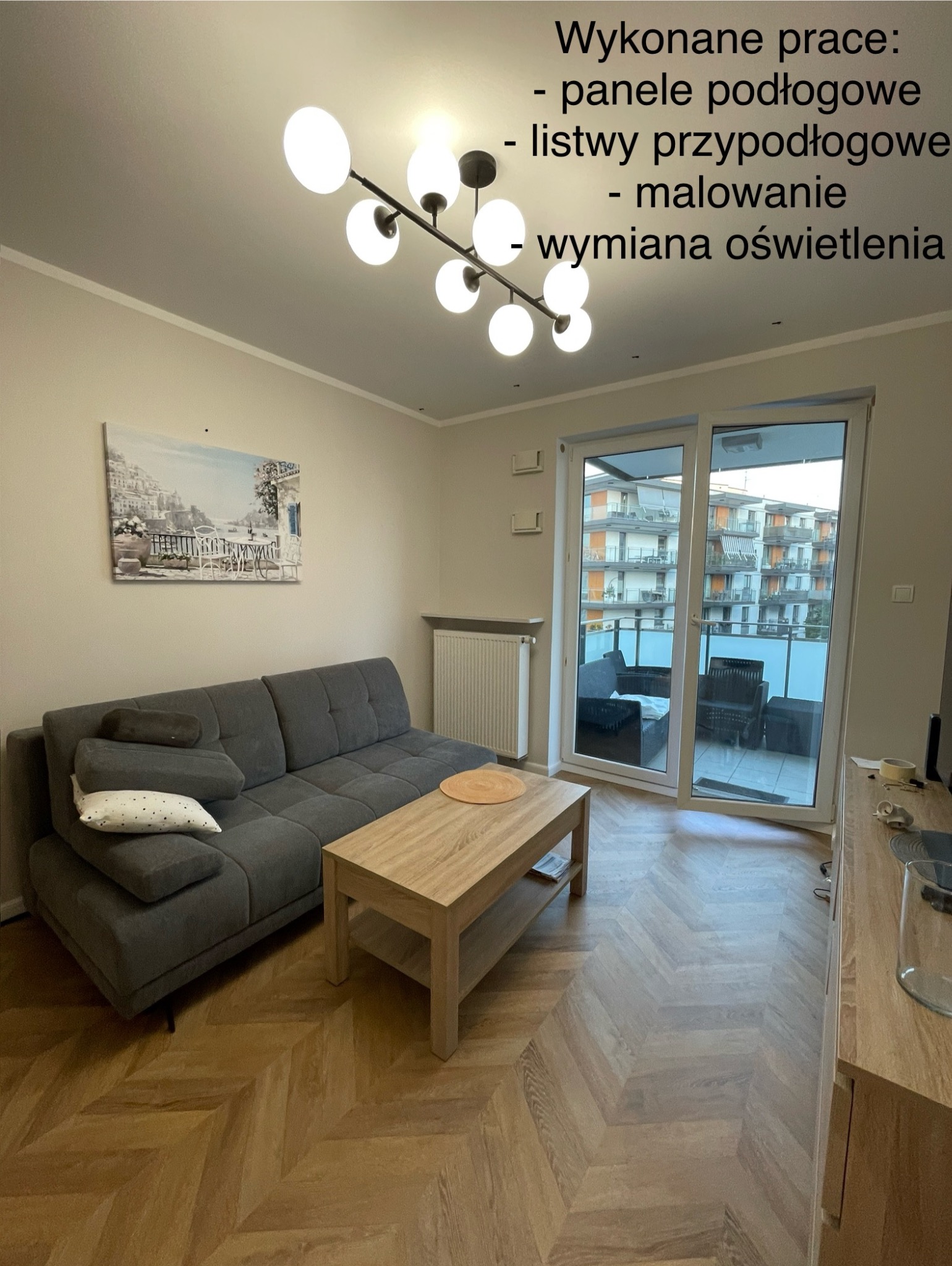 Salon po remoncie: parkiet w jodełkę, świeżo pomalowane ściany i nowoczesna lampa sufitowa. Widok na balkon z meblami.