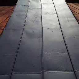 GROTBUDMS SPÓŁKA Z OGRANICZONĄ ODPOWIEDZIALNOŚCIĄ - Szare, metalowe panele na dachu po świeżym pomalowaniu, widoczne ślady pędzla i łączenia paneli.