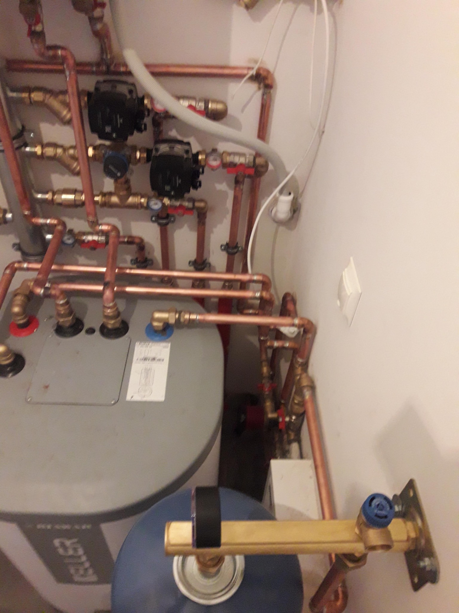 Kompleksowa instalacja grzewcza z kotłem, rurami miedzianymi, zaworami i pompami obiegowymi w kotłowni. Widok z góry, oświetlenie sztuczne.