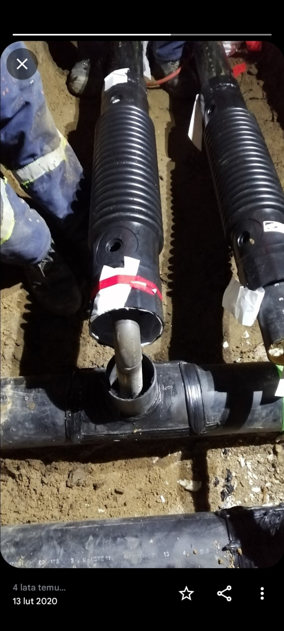 Instalacja podziemnej kanalizacji z rur karbowanych i kształtek, widoczne łączenia z uszczelkami i taśmą izolacyjną, częściowo zasypane ziemią.