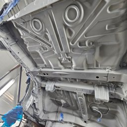 EMTE-SERWIS - Spód samochodu po nałożeniu srebrnej powłoki ochronnej, widoczne zabezpieczenia folią i taśmą malarską na elementach.