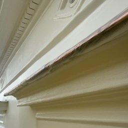 ZAKŁAD WIRTUALNEJ RZECZYWISTOŚCI-The Property of Virtual Universe Piotr Kuśmierski - Detal dekoracyjny sufitu z elementami sztukaterii i kratką wentylacyjną, świeżo pomalowany na jasny kolor, z zabezpieczoną folią listwą.