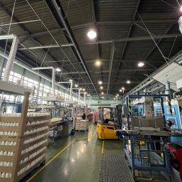 ZAKŁAD WIRTUALNEJ RZECZYWISTOŚCI-The Property of Virtual Universe Piotr Kuśmierski - Wnętrze hali produkcyjnej z liniami technologicznymi, wózkiem widłowym i pracownikami. Widoczna instalacja wentylacyjna pod sufitem. Produkcja opakowań.