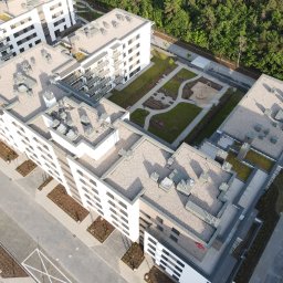 ArchUp - Nowoczesny kompleks budynków mieszkalnych z zielonym dziedzińcem i placem zabaw, widok z lotu ptaka, jasna kolorystyka elewacji, geometryczny układ dachów.