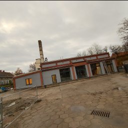 Budomex - Budynek po renowacji elewacji w Szprotawie, widoczny komin, szara elewacja z ceglanymi detalami i drabina oparta o ścianę.