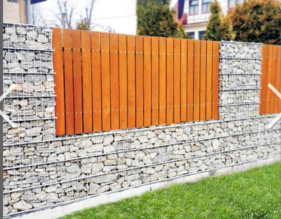 Nowoczesne ogrodzenie: gabiony wypełnione kamieniem, połączone z drewnianymi panelami. Estetyczne wykończenie posesji z zielonym trawnikiem w tle.