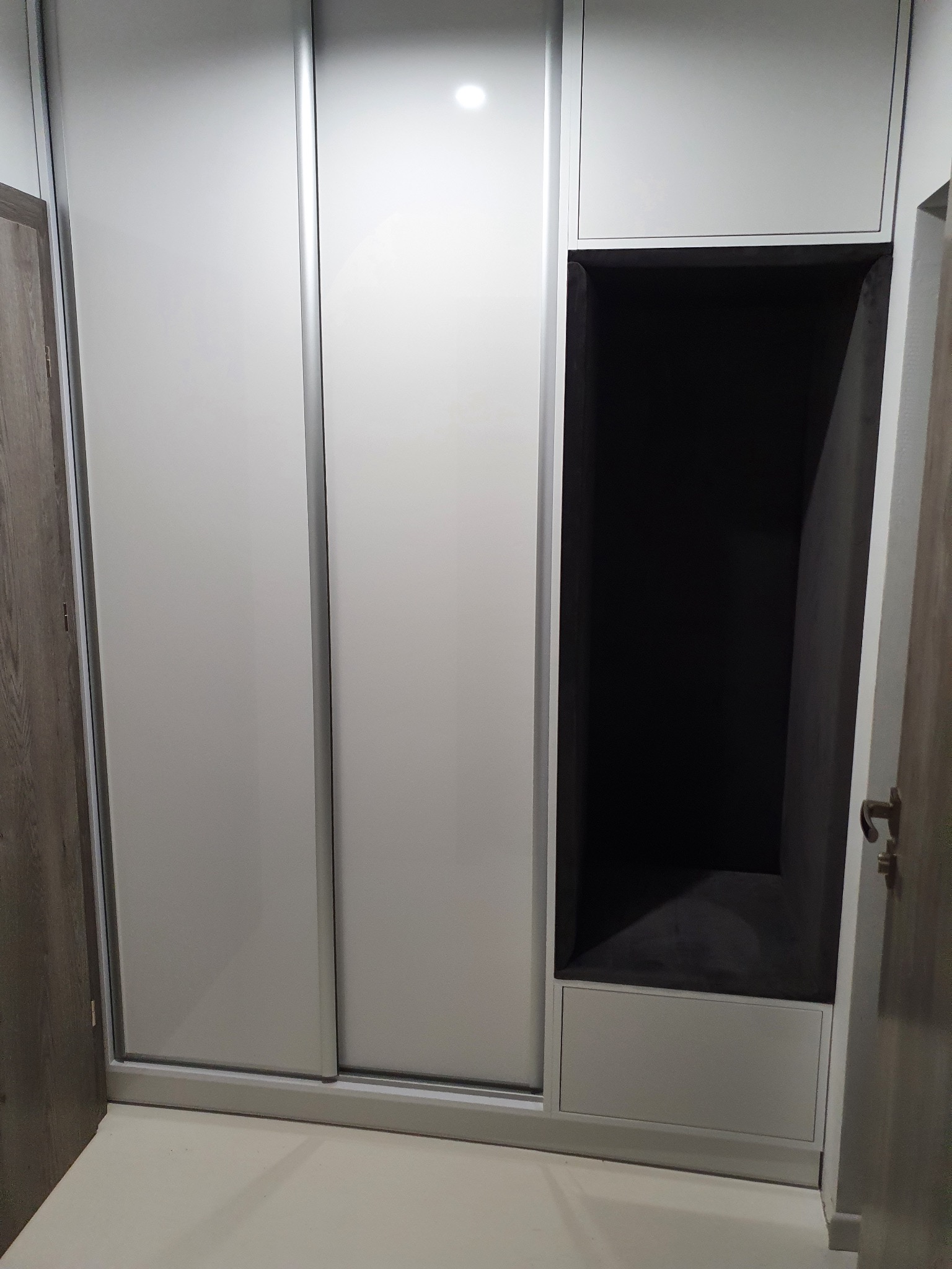 Nowoczesna szafa wnękowa z przesuwnymi drzwiami i otwartą półką, wykonana na wymiar w Gorzowie Wielkopolskim. Jasne fronty, srebrne obramowania.