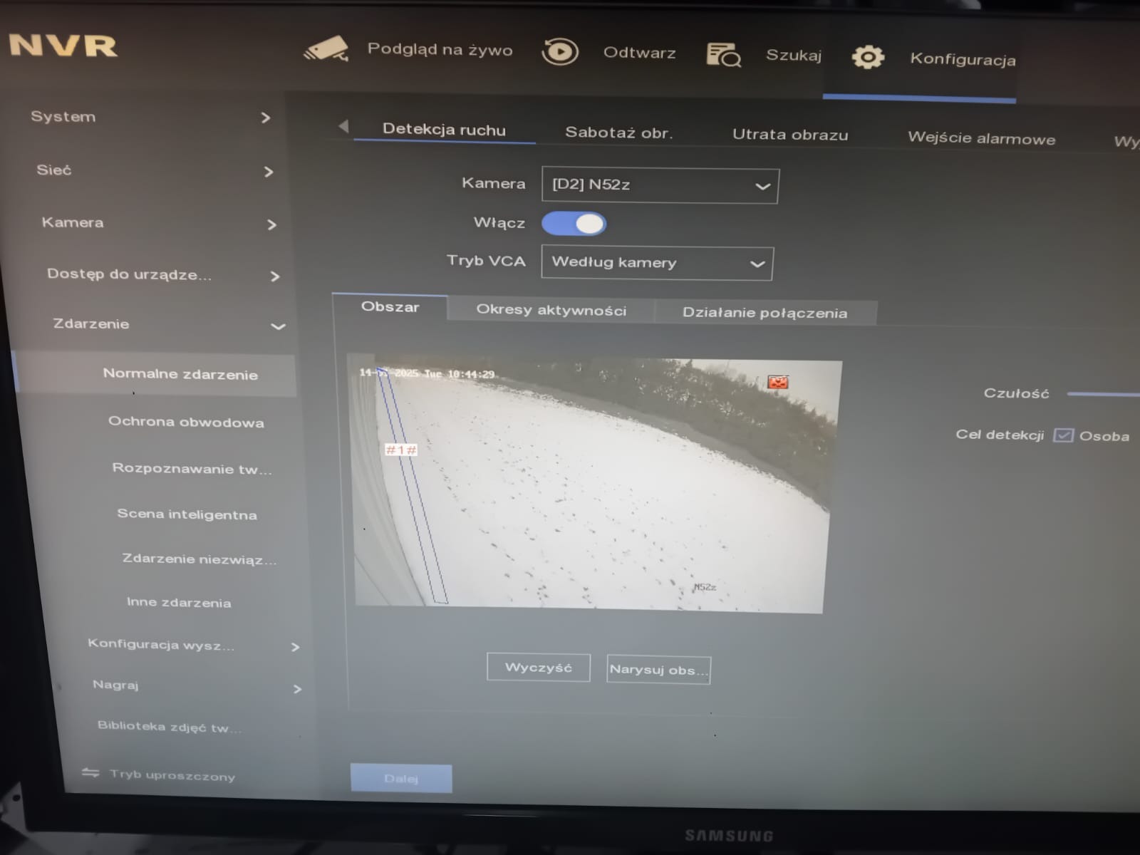 Interfejs konfiguracji systemu monitoringu wizyjnego NVR na ekranie monitora, widoczna opcja detekcji ruchu z ustawieniami kamery [D2] N52z, zaznaczony obszar detekcji na podglądzie z kamery...