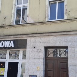 LIS-BUD BARTŁOMIEJ LISIECKI - Fasada budynku z widocznymi śladami zużycia i odpadającą farbą, nad wejściem do lokalu z szyldem 'ODNOWA' - kontrast między zaniedbaną elewacją a nazwą lokalu.