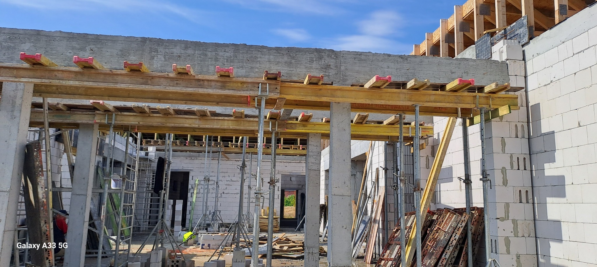 Budowa domu z betonu komórkowego: widoczne ściany z bloczków, betonowy wieniec oraz drewniane szalunki pod strop.