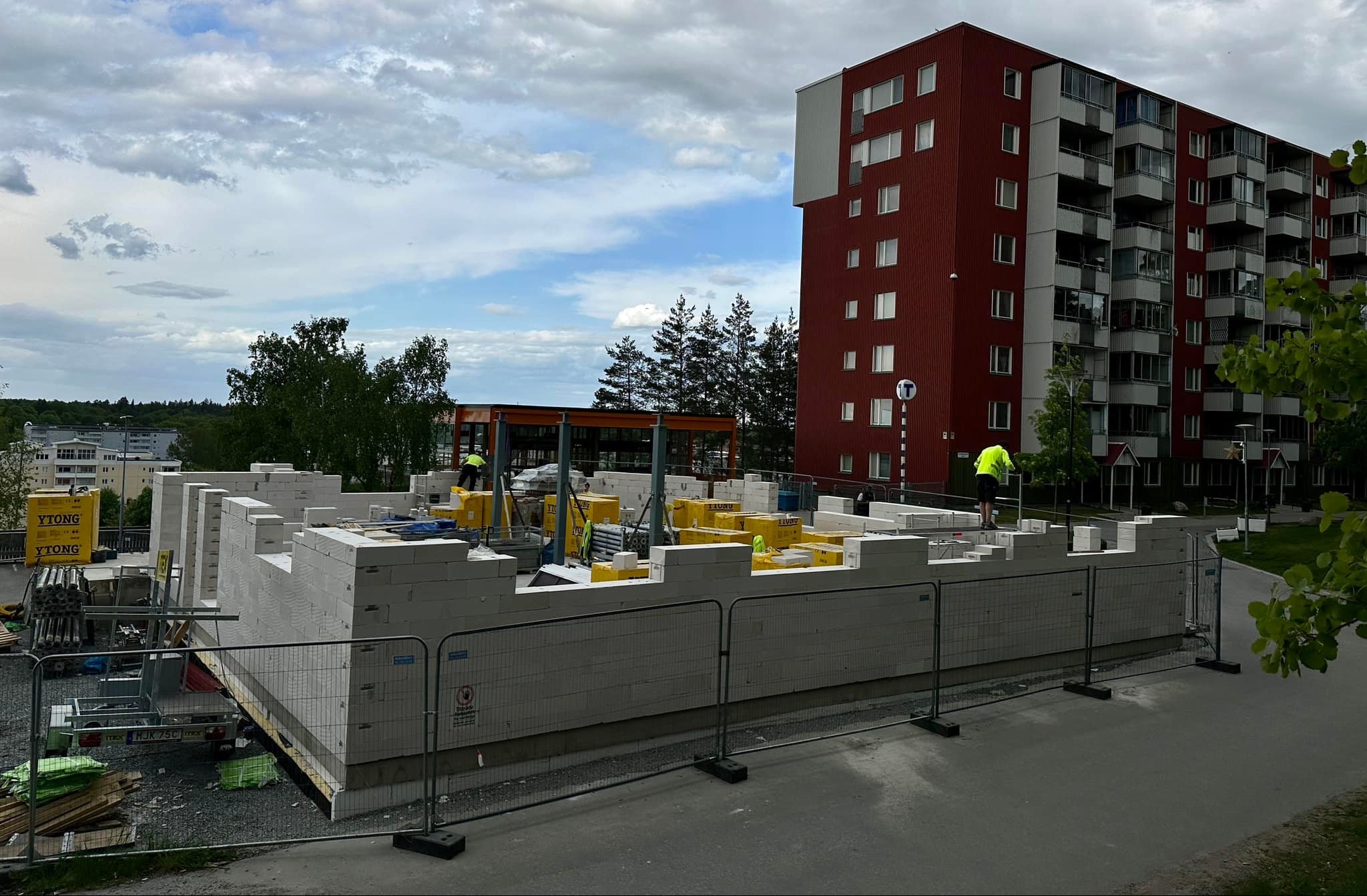 Budowa ścian z bloczków Ytong na placu budowy w Hallunda, widoczne materiały budowlane i pracownicy w odblaskowych kamizelkach.