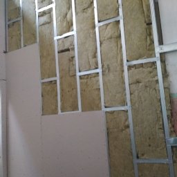 BARTOR - Konstrukcja metalowa z izolacją z wełny mineralnej, częściowo zakryta płytami gipsowo-kartonowymi, widoczne ślady montażu na płytach.