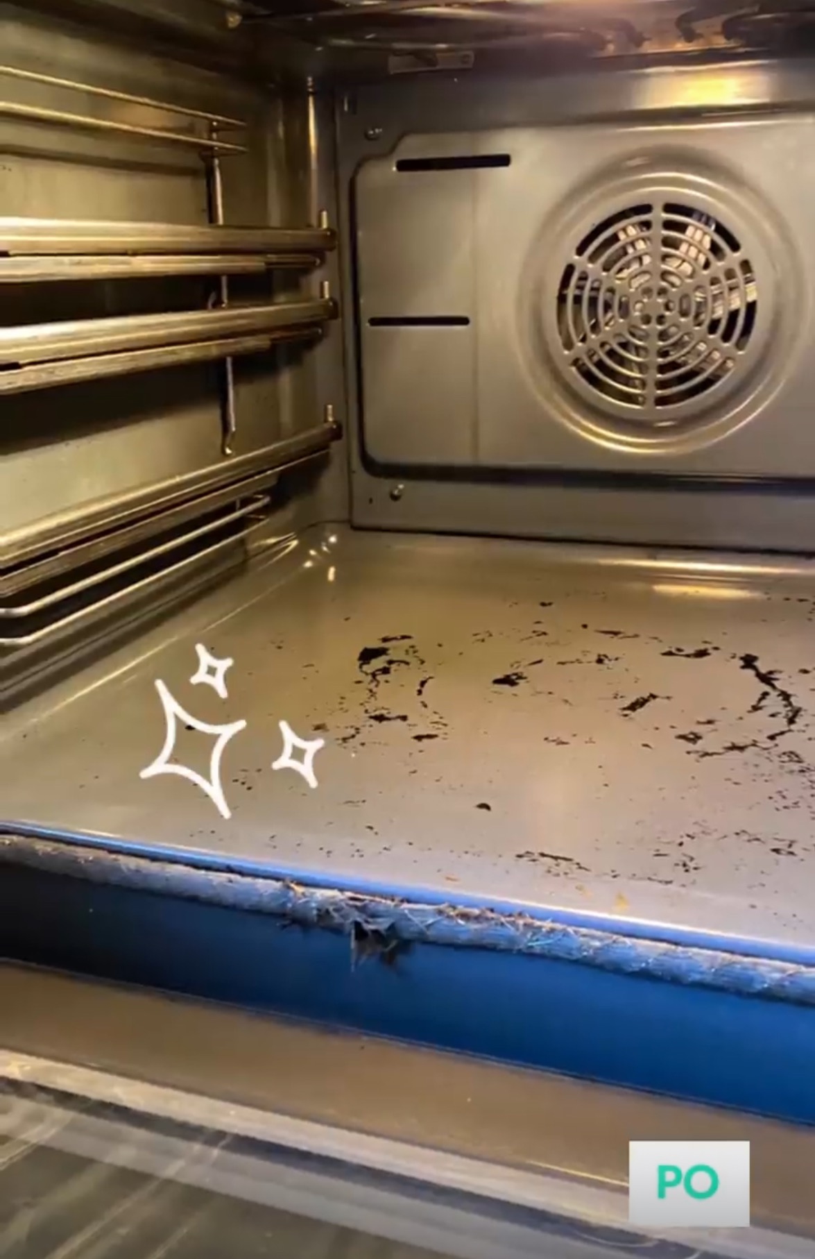 Wnętrze brudnego piekarnika przed czyszczeniem, widoczne przypalone resztki jedzenia na dnie i ściankach, z elementami grzejnymi na górze.