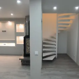 Jasne, przestronne wnętrze po remoncie w Roźwienicy z drewnianą podłogą, spiralnymi schodami i wnękami oświetlonymi punktowo w ścianie.