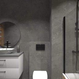 Remonikr - Nowoczesna łazienka z szarą, betonową fakturą na ścianach, białą umywalką nablatową o geometrycznym kształcie, okrągłym lustrem i kabiną prysznicową z czarną armaturą.