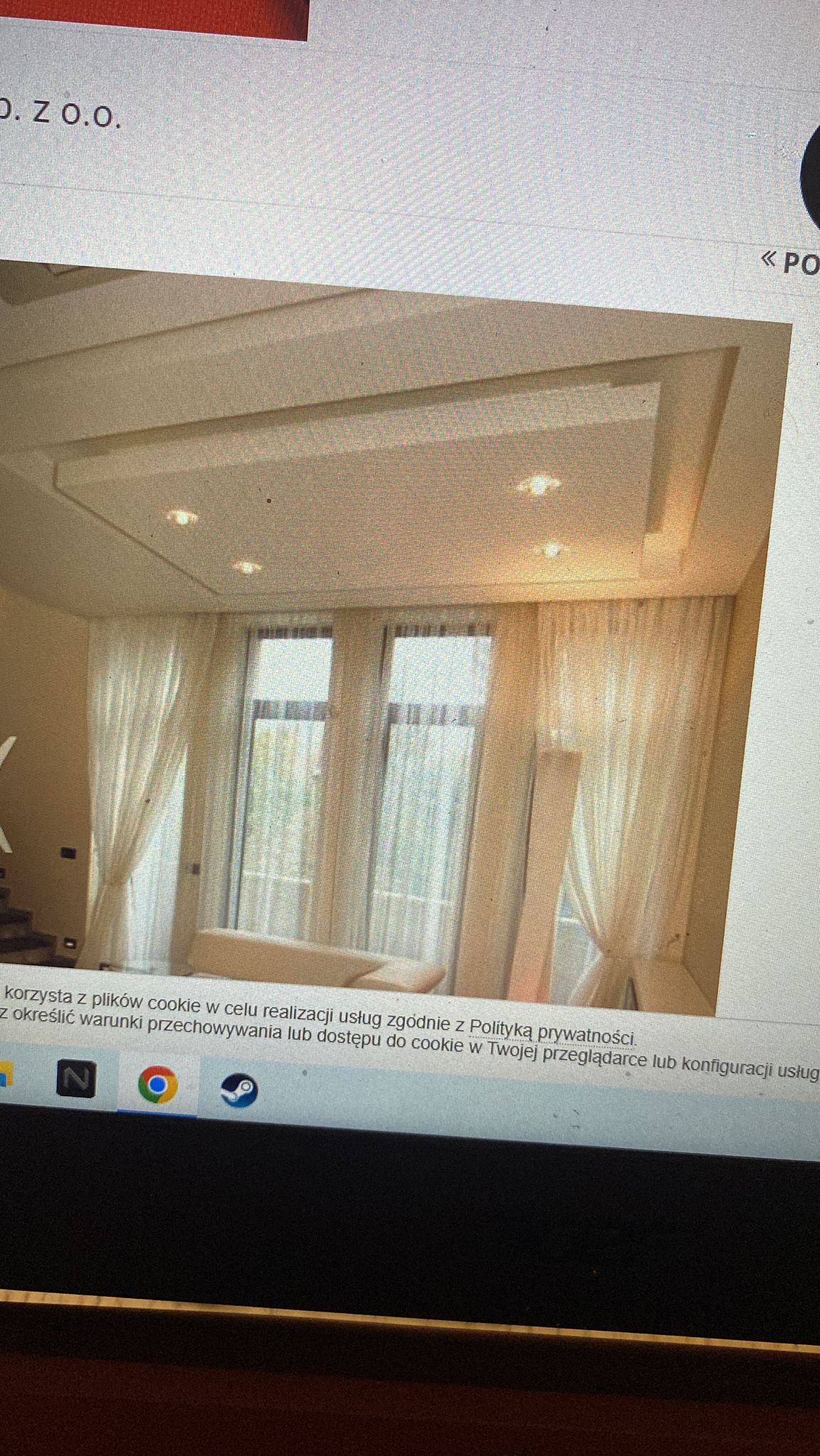 Eleganckie wnętrze z kremowymi zasłonami, oświetleniem punktowym w podwieszanym suficie i widokiem z okna, sfotografowane pod kątem z dołu.