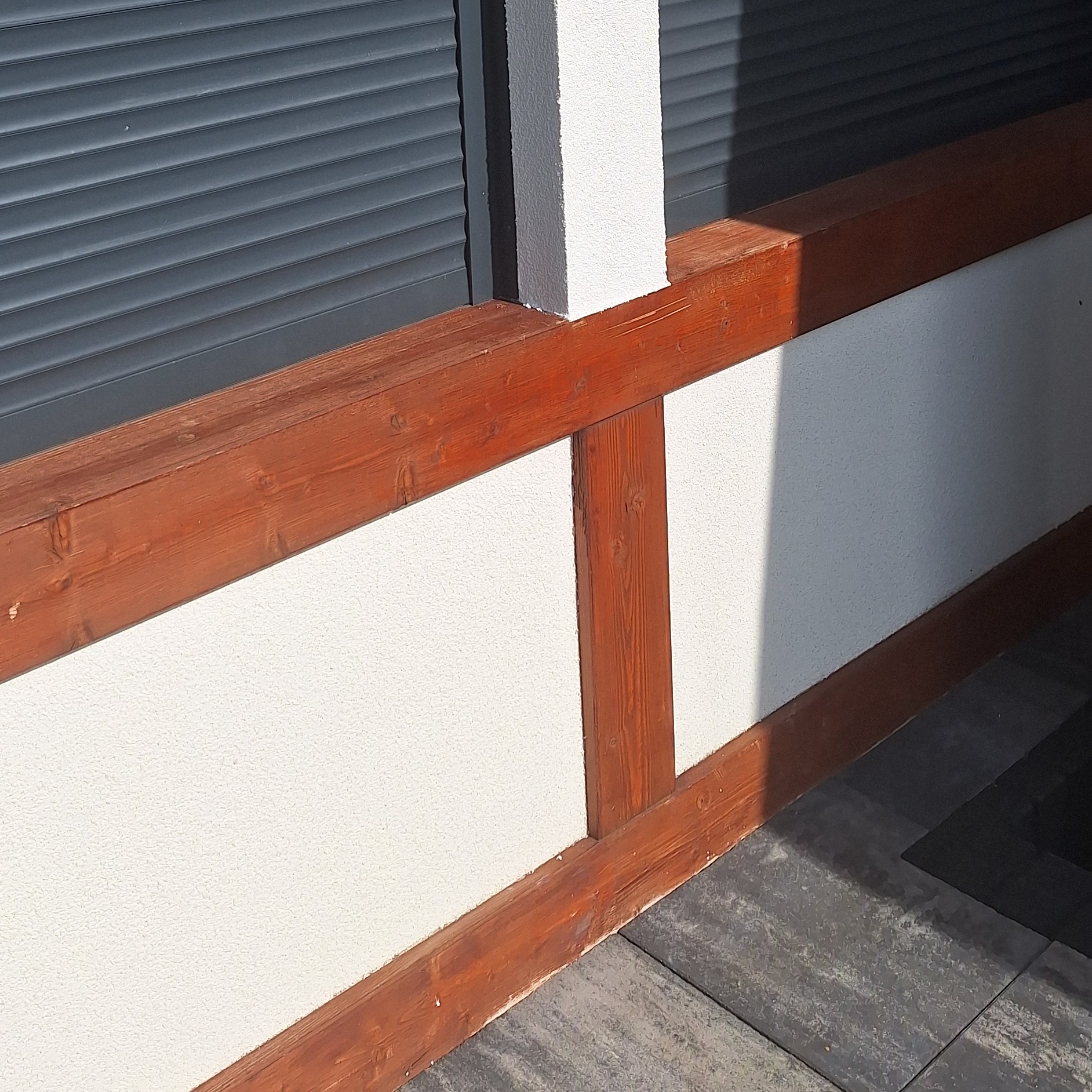 Wykończona ściana zewnętrzna z drewnianą konstrukcją i szarymi roletami okiennymi, widok z dołu.