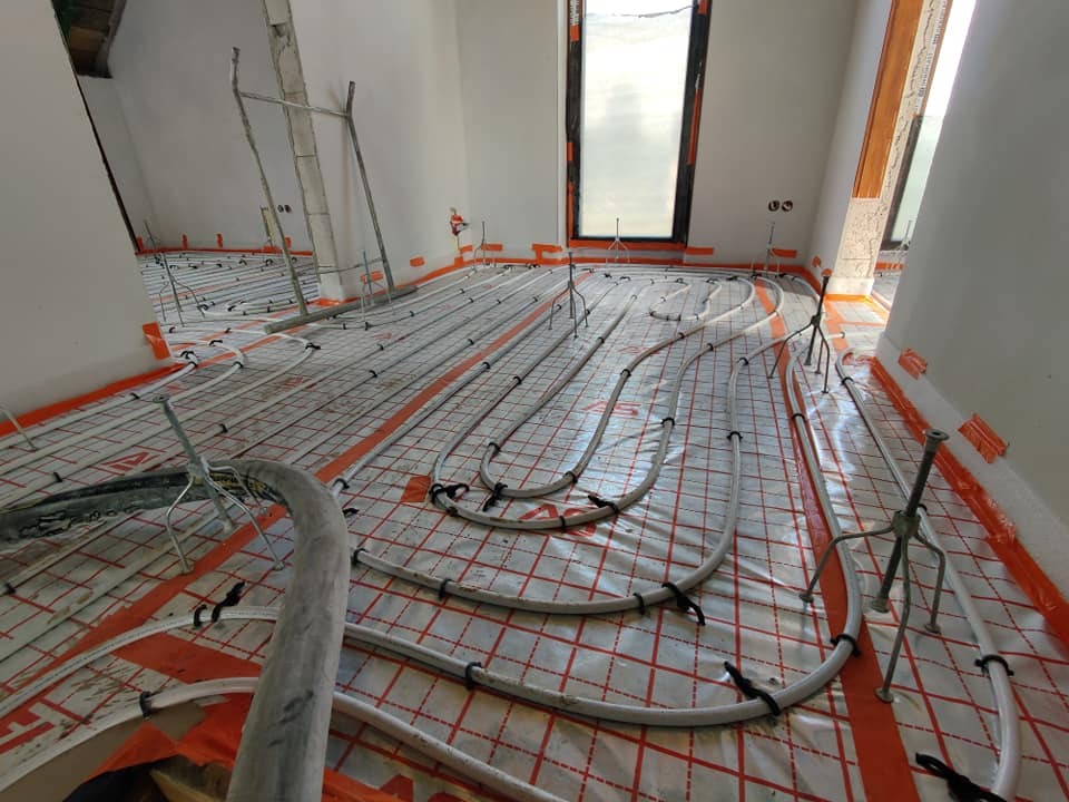 Montaż ogrzewania podłogowego w nowym domu w Wyszkowie, rury grzewcze rozłożone na folii z siatką, widoczne uchwyty mocujące.