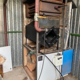 Zicher Technika Grzewcza Mateusz Dziembowski - Wnętrze pieca z widocznymi elementami instalacji w Jasin, zanieczyszczone elementy wskazują na potrzebę serwisu.