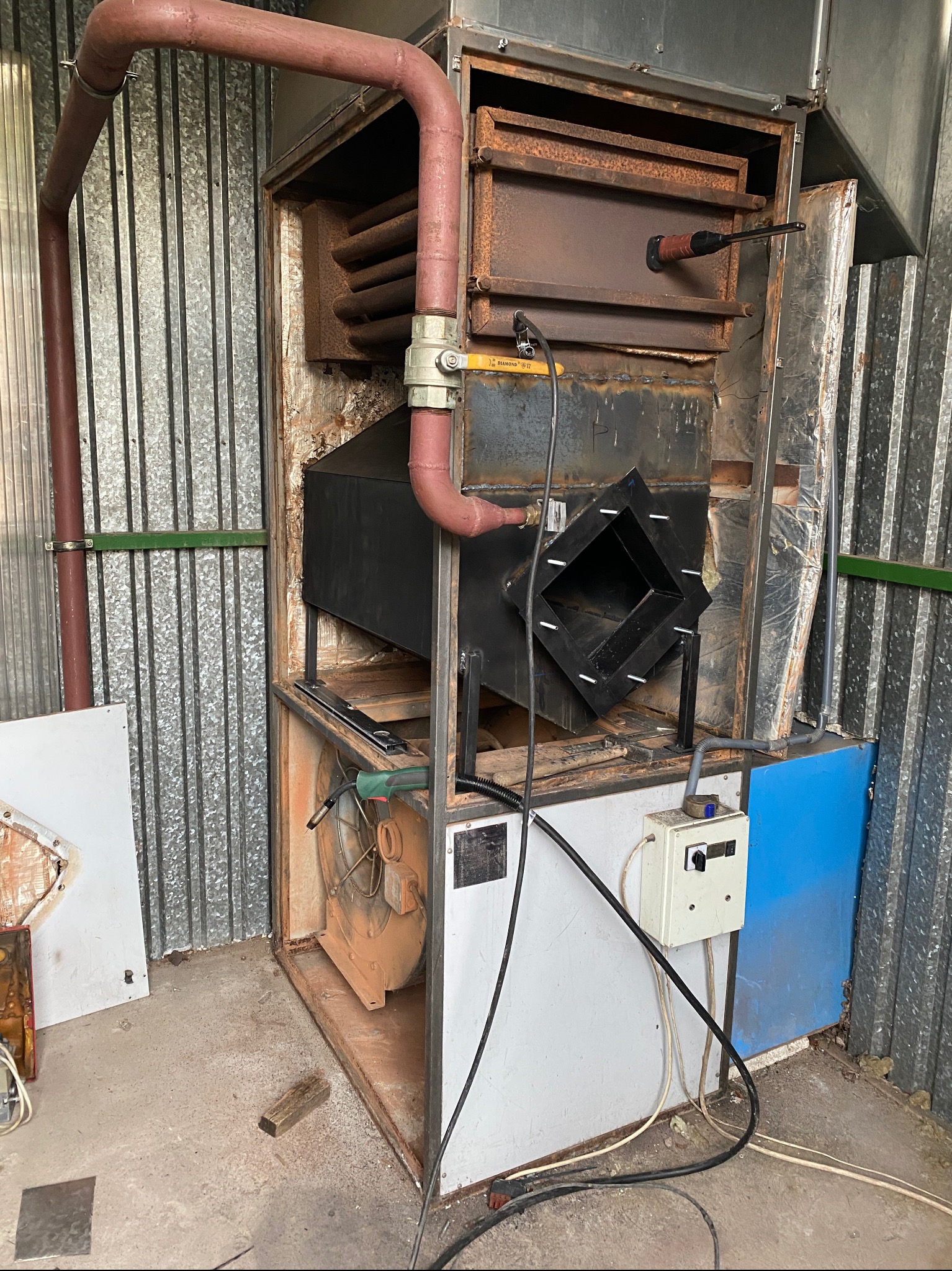 Wnętrze pieca z widocznymi elementami instalacji w Jasin, zanieczyszczone elementy wskazują na potrzebę serwisu.